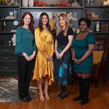 Four interior design students posing in front of a bookcase