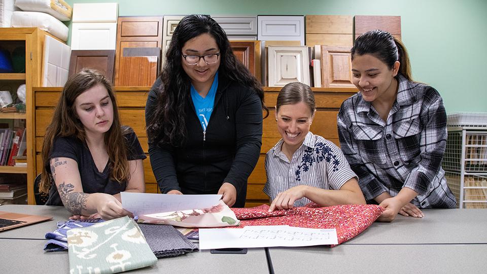 Four interior design students examining upholstery fabric